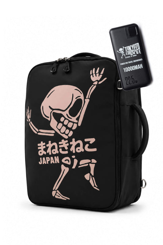 A black insulated lunch bag featuring a pink dancing skeleton graphic and Japanese text reading 'Machinico JAPAN'. A black smartphone with 'Trick or Treat' branding is shown tucked into the side pocket of the bag.