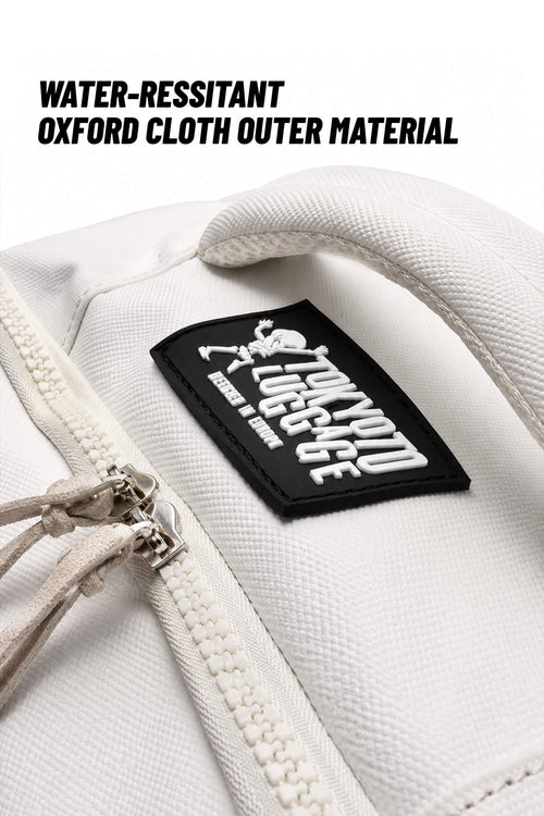 Close-up of a white textured fabric bag with a black rectangular patch reading 'Tough Love Lodge' and text above stating 'WATER-RESSITANT OXFORD CLOTH OUTER MATERIAL.'.